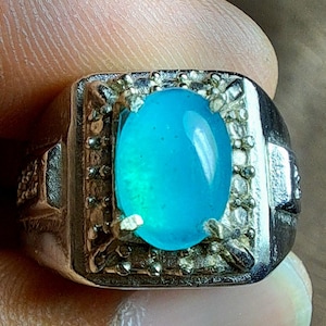 Peut inclure: Une bague en argent avec une grande pierre précieuse ovale de couleur bleu clair sertie dans un décor en argent.