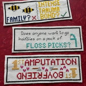 Puede incluir: Tres piezas rectangulares de punto de cruz blanco con bordes negros. La pieza superior dice "INTENSE TRAUMA BOND?" con una marca de verificación y dos abejas amarillas. La pieza del medio dice "¿Alguien quiere ir a medias en un paquete de FLOSS PICKS?" La pieza inferior dice "1er AMPUTACIÓN NOVIO 1er" con corazones y un número uno dorado.