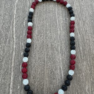May include: A black, white, and maroon beaded necklace with sparkly beads.