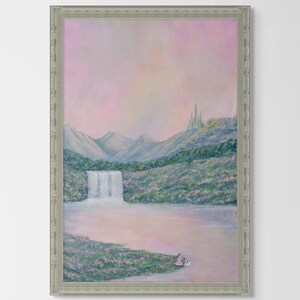May include: A framed landscape painting depicts a waterfall cascading into a lake, with mountains in the background. The artwork features a soft color palette of pink, blue, and green, with a castle on a distant hill. The frame is silver.