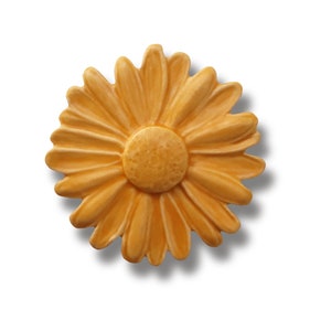 Puede incluir: Una flor de margarita de cerámica amarilla con un diseño en relieve. La flor tiene un centro de color amarillo ligeramente más oscuro.