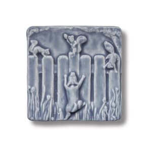 May include: A square, blue ceramic tile depicting a relief scene of squirrels and a cat climbing a fence. The fence is made of vertical posts, and the background includes stylized foliage. The tile has a slightly textured surface.
