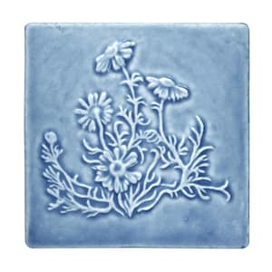 May include: A square, light blue ceramic tile with a raised floral design. The design features several daisies with detailed petals and stems. The tile has a matte finish and a slightly textured surface.