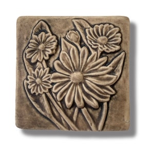 Puede incluir: Un azulejo de cerámica con un diseño en relieve de flores marrones. Las flores están agrupadas y tienen un aspecto realista y detallado.