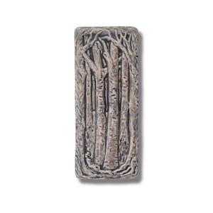 May include: A rectangular ceramic tile with a raised design of a group of trees. The trees are brown and grey with a textured surface. The tile is a light brown colour.