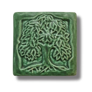 May include: A green ceramic tile featuring a raised design of a tree with leaves and roots.