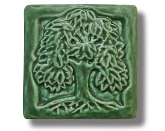 May include: A green ceramic tile with a raised design of a tree with leaves and roots.