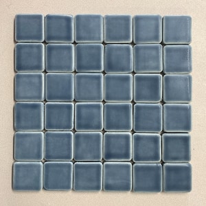 May include: A sheet of mosaic tiles, featuring thirty-six small, square tiles in a grid. Each tile is a muted blue-grey with a glossy finish. The tiles are arranged on a neutral background, suitable for home decor, with each tile measuring approximately 2.5 cm.