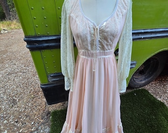 May include: A long, pink, vintage dress with lace sleeves and a lace bodice. The dress has a gathered skirt and a tie at the waist.