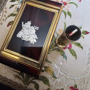 May include: A vintage, brass-framed, rectangular box with a brown tortoiseshell-like interior. The box features a silver-colored map of Austria with the word "ZON" printed on it. A brass cylinder with a small hole in the top is also pictured.