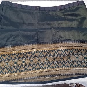 May include: A black skirt with a gold and green patterned trim. The skirt is made of a silky fabric and has a waistband.