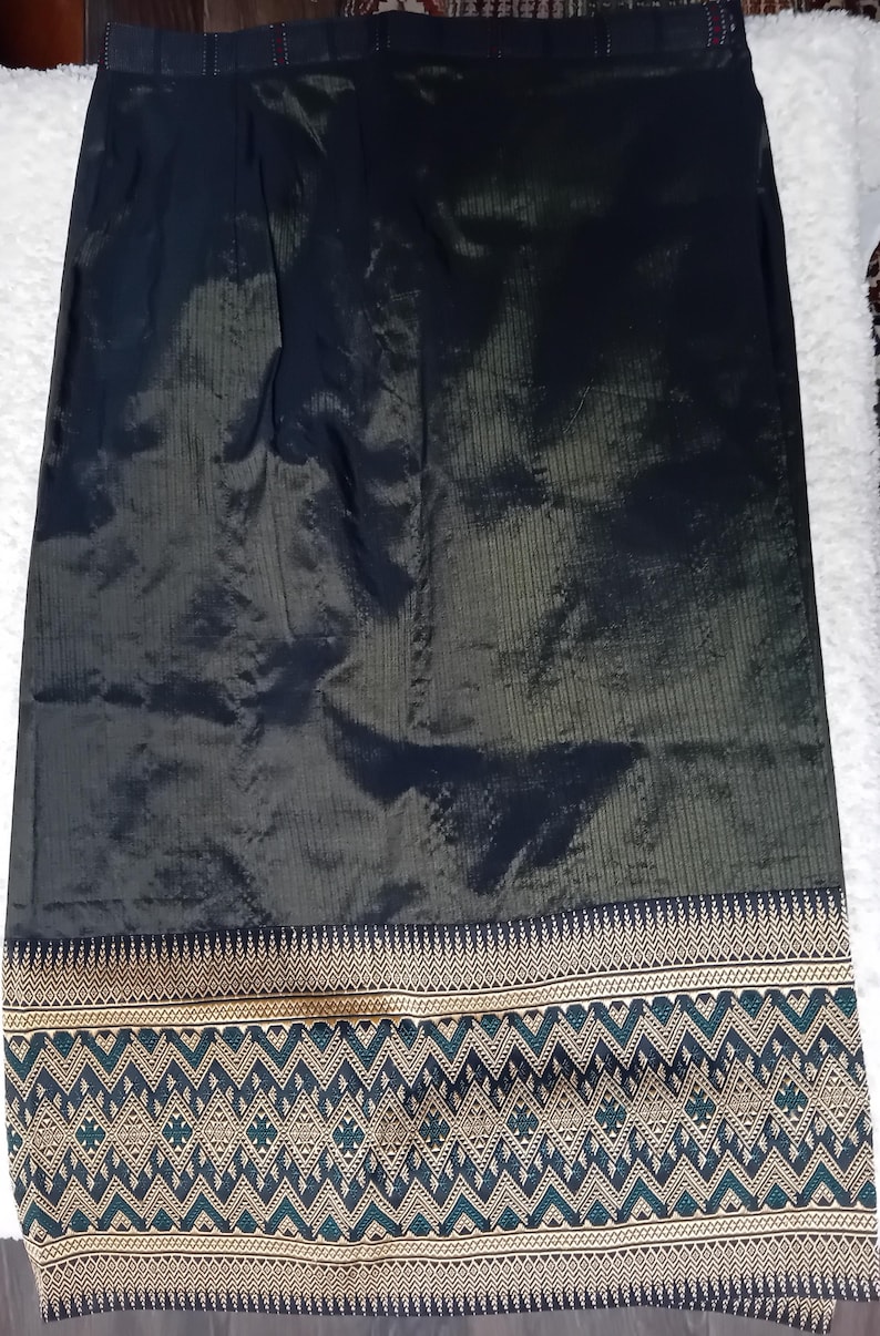 May include: A black and green skirt with a gold and green embroidered border. The skirt is made of a silky fabric.