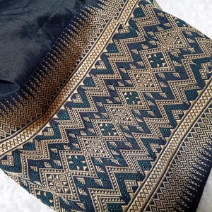 May include: Black fabric with a gold and green geometric pattern. The fabric has a woven texture and a subtle sheen.