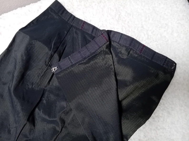 May include: Black skirt with a zipper closure and a plaid lining. The skirt is made of a smooth, silky fabric.