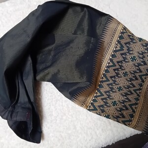 May include: A black and gold patterned fabric with a geometric design. The fabric is folded in half and has a dark green and gold trim.