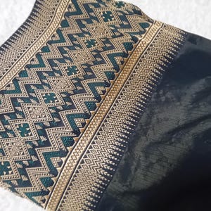 May include: Black fabric with a gold and green geometric pattern. The fabric has a woven texture and a subtle sheen.