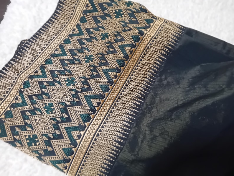 May include: Black fabric with a gold and green geometric pattern. The fabric has a woven texture and a subtle sheen.