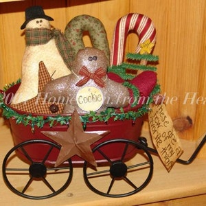 May include: A red wagon filled with Christmas decorations, including a snowman, gingerbread man, candy cane, and a star. The wagon has black wheels and is decorated with green garland. The text "These are a few of my favorite things" is written on a tag attached to the wagon.