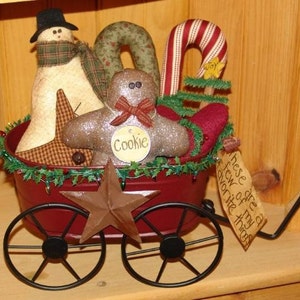 May include: A red metal wagon filled with Christmas decorations, including a snowman, gingerbread man, candy cane, and a star. The wagon has a sign that reads "These are a few of my favorite things".