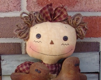 May include: A handmade rag doll with brown yarn hair, a plaid fabric bow, and a smiling face. The doll is holding two brown fabric birds.