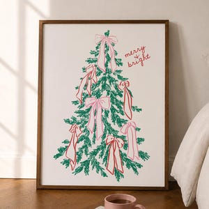 May include: A framed wall art print featuring a green line-art Christmas tree decorated with pink bows and the handwritten red text merry bright. The artwork is displayed in a dark wood frame, showcasing a festive holiday illustration.