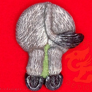 May include: A gray and black donkey figurine with a green tail. The donkey is standing on its hind legs with its front legs in the air. The figurine is made of a textured material and has a realistic appearance.