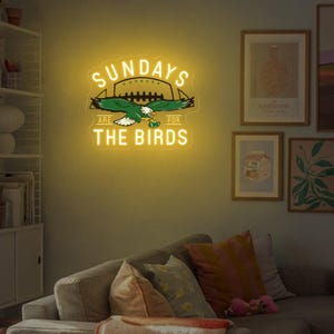 Może przedstawiać: Neonowy znak z napisem "Sundays are for the Birds" i zielonym i białym orłem z piłką nożną w szponach.