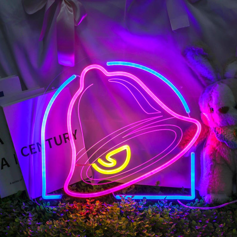 May include: A neon sign shaped like a bell with a pink outline and a blue outline. The bell has a yellow 'S' inside. The sign is lit up with pink, blue, and yellow lights.