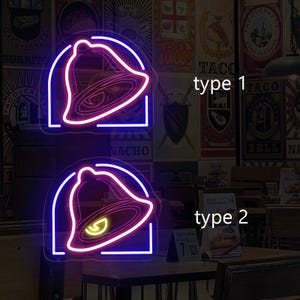 May include: Two neon signs with a Taco Bell bell design. The top sign is blue and pink, and the bottom sign is pink and blue. The signs are labeled "type 1" and "type 2".