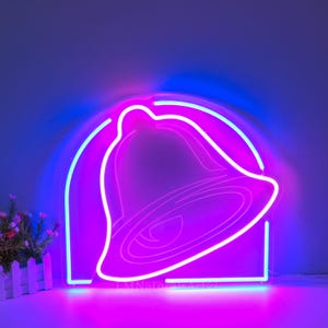 May include: A neon sign shaped like a bell with a pink and blue glow. The bell is outlined in white and the background is a dark purple.