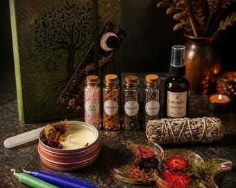 May include: A green journal with a tree design, a moon bookmark, four small glass vials containing rose quartz, calendula, mugwort, and lavender, a lavender pillow spray bottle, a sage bundle, a candle in a tin, and two taper candles.