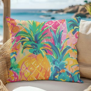 May include: A colorful throw pillow with a tropical pineapple pattern. The pillow features a bright yellow pineapple with green leaves and pink, blue, and yellow accents.