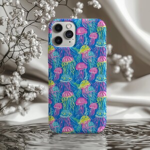 May include: A phone case with a vibrant pattern of colorful jellyfish on a blue background. The jellyfish are in shades of pink, yellow, and blue with long, flowing tentacles. The case has a glossy finish and a camera cutout.