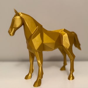 May include: A golden, geometric horse sculpture. The horse is standing with its head up and tail out. The sculpture is made of many flat, angled surfaces, giving it a modern, abstract look. The horse is a solid color and appears to be made of plastic.