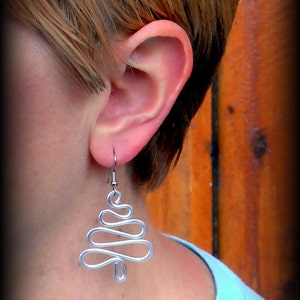 May include: Silver wire earrings shaped like a Christmas tree.