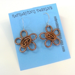 May include: A pair of copper wire flower earrings with a silver hook. The earrings are displayed on a blue card with the text "Refreshing Designs refreshingdesigns.etsy.com".