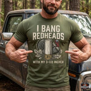 May include: Olive green t-shirt with the text "I BANG REDHEADS" above a turkey and a 3 1/2 inch shotgun shell. The text "WITH MY 3-1/2 INCHER" is below the shell. The shirt is being pointed at by the person wearing it.
