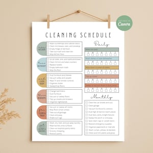 Puede incluir: Un póster blanco de programación de limpieza con un diseño minimalista, que enumera las tareas diarias y mensuales. El texto "CLEANING SCHEDULE" está en la parte superior. El póster está sujeto con clips de madera.