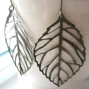 May include: A pair of silver leaf-shaped earrings with a delicate, intricate design.