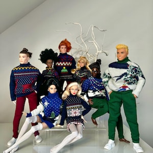 May include: A group of dolls wearing festive holiday sweaters with various patterns, including reindeer, snowflakes, and Christmas trees. The dolls are posed in a playful and festive manner, creating a cheerful holiday scene.