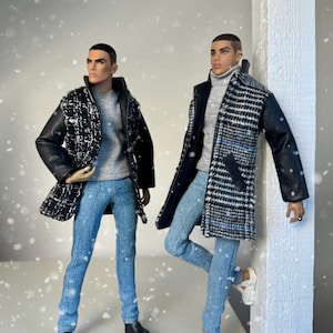Può includere: Due bambole alla moda vestite con eleganti outfit invernali. Una bambola indossa un cappotto a fantasia bianco e nero con maniche in pelle nera, un maglione grigio e jeans blu. L'altra bambola indossa un cappotto simile, un dolcevita grigio e jeans blu.