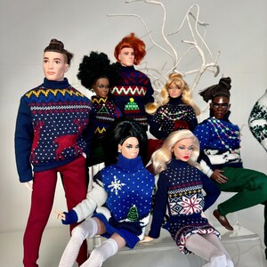 May include: A group of dolls wearing festive holiday sweaters with various patterns, including snowflakes, reindeer, and Christmas trees. The dolls are arranged in a seated and standing position, creating a playful and festive scene.