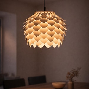 May include: A pendant light fixture with a layered, petal-like design. The light fixture is suspended from a black cord and emits a warm, inviting glow. The light is above a wooden table.