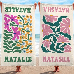 K&ouml;nnte beinhalten: Zwei Strandt&uuml;cher mit Blumendesigns und Namen. Ein Handtuch zeigt den Namen "NATALIE" in Gr&uuml;n, mit rosa und blauen Blumen. Das andere Handtuch hat den Namen "NATASHA" in Rosa, mit rosa Blumen und gr&uuml;nen Bl&auml;ttern.