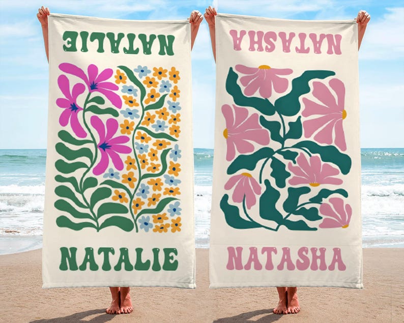 K&ouml;nnte beinhalten: Zwei Strandt&uuml;cher mit Blumendesigns und Namen. Ein Handtuch zeigt den Namen "NATALIE" in Gr&uuml;n, mit rosa und blauen Blumen. Das andere Handtuch hat den Namen "NATASHA" in Rosa, mit rosa Blumen und gr&uuml;nen Bl&auml;ttern.