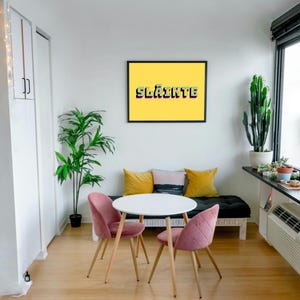 May include: A white table with two pink chairs and a black bench with yellow and black cushions. A framed print with a yellow background and the word "Sl&aacute;inte" in rainbow colours hangs on the wall.
