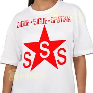 May include: White t-shirt with a red star graphic and the text "SIGUE SIGUE SPUTNIK". The star has three "S" letters inside. The shirt is a short-sleeved crew neck.