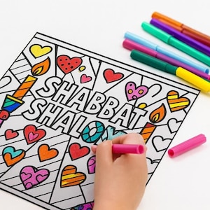 May include: A coloring page with the words "Shabbat Shalom" surrounded by hearts and candles. A hand is coloring the page with a pink marker. Several colored markers are visible in the background.