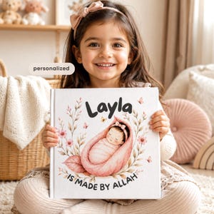 Peut inclure: Un livre à couverture rigide blanc intitulé Layla IS MADE BY ALLAH, présentant une illustration centrale d'un bébé emmailloté dans une forme de pétale rose, entouré de branches florales délicates, de petits papillons et le mot personalized.