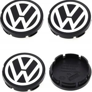 Könnte beinhalten: Ein Set aus vier runden schwarz-weißen Volkswagen Radnabendeckeln. Drei Deckel zeigen das ikonische VW-Logo auf der Vorderseite, während ein Deckel umgedreht ist, um die schwarze Kunststoffunterseite mit eingeprägten Teilenummern zu zeigen.